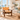 A mid-century modern accent chair with a dark brown wooden frame and tan leather seat and backrest, styled in a bright, sunlit living room with a white sofa and ocean view.