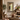 A rectangular wall mirror with an ornate textured frame hangs on a warm beige wall in a styled living room. 