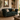 A dark green velvet chesterfield loveseat sofa with nailhead trim and wooden legs, styled in a warm, rustic living room with beige and patterned throw pillows.