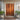 Wooden front door with decorative frame, potted plants, and a large teak floor mat handcrafted from solid teak timber
