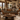 A rustic brown leather loveseat sofa with patterned rust and brown throw pillows, set in a cozy mountain-style living room with a wooden coffee table, stone fireplace, and mountain views.