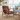 A mid-century modern accent chair with a brown leather cushioned seat and backrest, paired with a light natural wood frame, shown in a bright coastal living room next to a blue sofa.