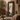 A tall, rectangular floor mirror with an ornate dark carved wooden frame stands in a rustic bohemian room.setting. 