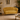 A curved yellow velvet loveseat with a scalloped backrest and slim gold legs