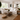 A white slipcovered modular sofa in a bright, modern living room with a wooden coffee table, beige rug, and potted plants.