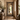 A tall, ornate full-length mirror with a carved rustic wood frame stands in a warm, bohemian-style hallway with beige walls, wooden floors, and natural light.