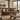 A brown leather sofa in a rustic, warm-toned living room setting with a wooden coffee table, woven rug, and large windows showing a scenic view.