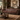 Westside leather Chesterfield sofa with deep button tufting and nailhead trim, styled in a classic, warm-toned living room with a wooden coffee table, patterned rug, bookshelves, and a framed landscape painting.