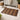 Brown and Natural colour Teak Mat on a tiled floor with a basket, slippers, and cabinet in the background.